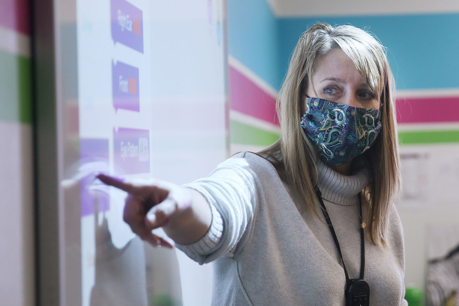 Technology teacher Krista Sweckard points to a button on the side of the smart board